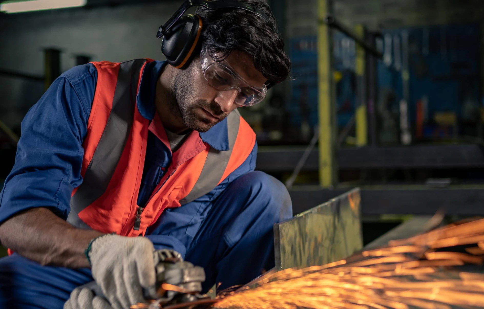 Ouvrier utilisant une meuleuse, étincelles au premier plan